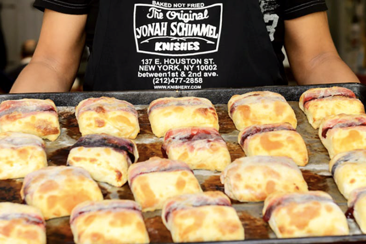 a person holding a tray of knishes