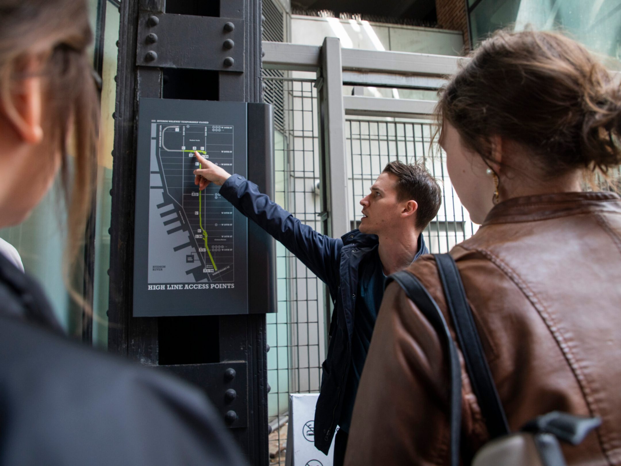 a man showing a group of people the map of the high line in nyc
