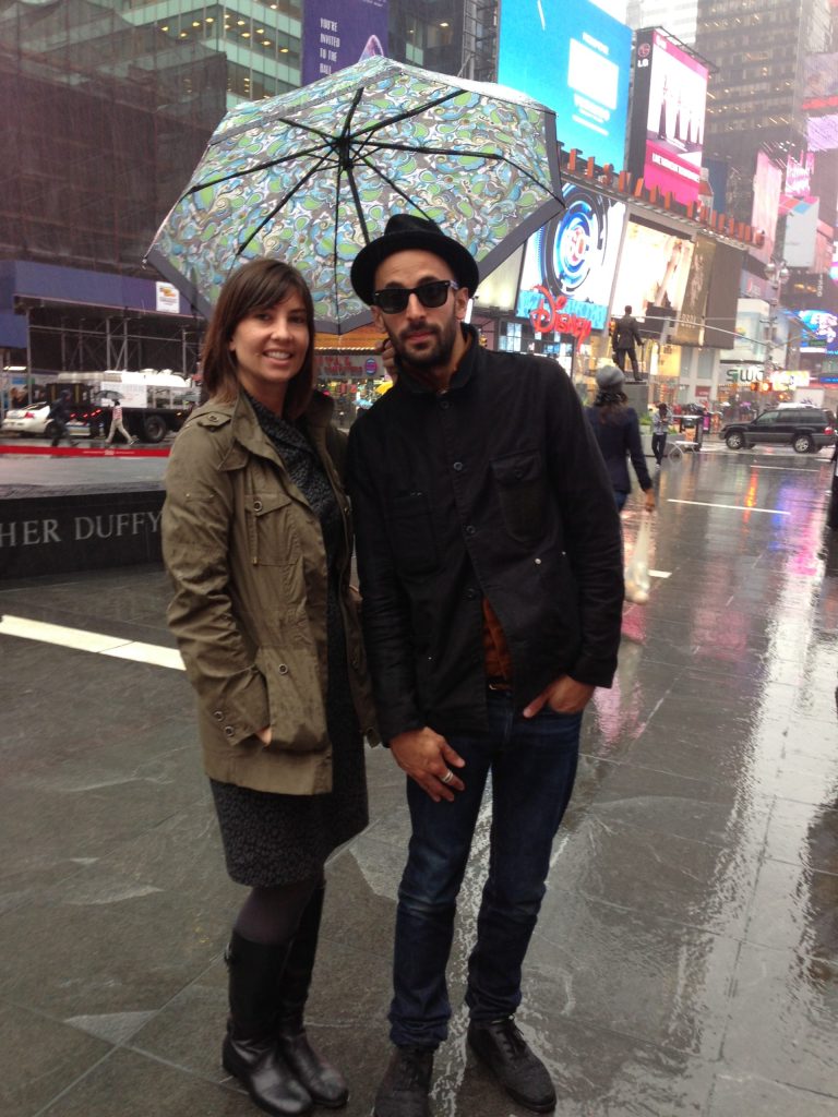 Lauren Beebe & JR in times square in the rain standing in the rain holding an umbrella